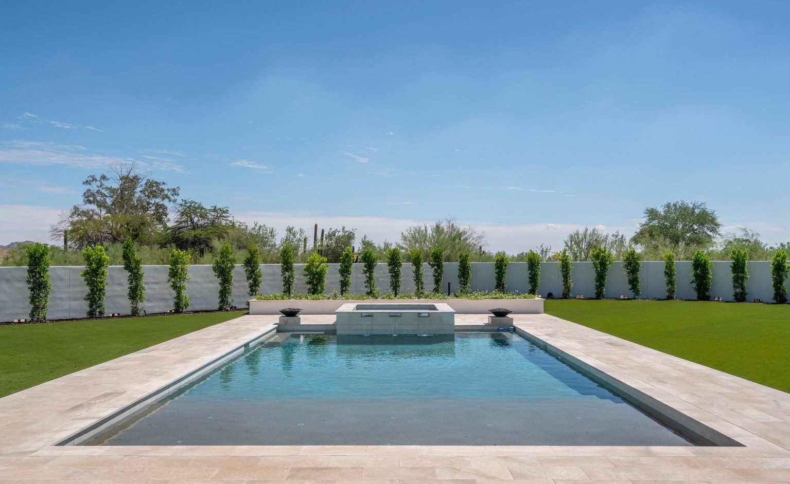 Rectilinear pool with travertine deck and manicured lawn at a Scottsdale residence