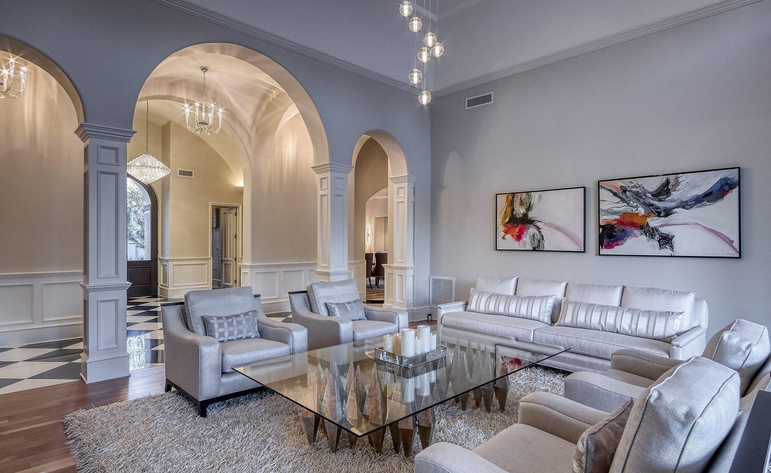 Formal living room with arched openings and a coffered entry beyond